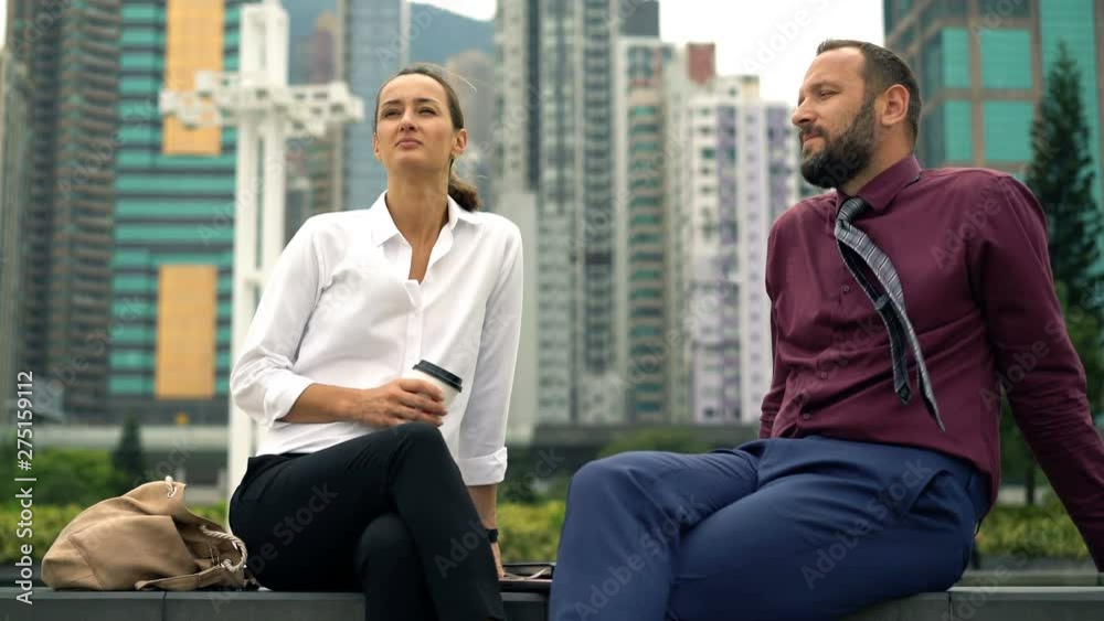 Young businessman and businesswoman relaxing, sitting on bench in the city Young businessman and businesswoman relaxing, sitting on bench in the city