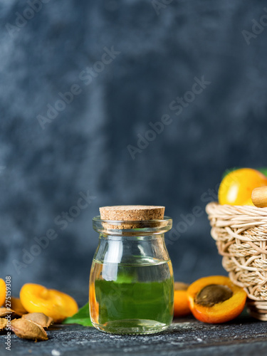 Glass bottle with apricot oil and fresh juicy apricots on the table