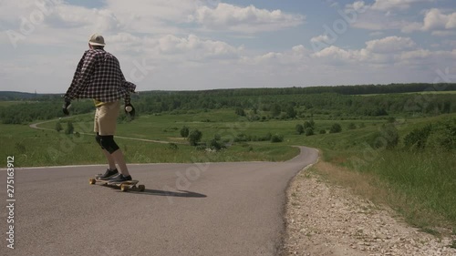 Man going down a hill on longbone in the forest Sunny summer day. Frame from a tripod, 4K photo