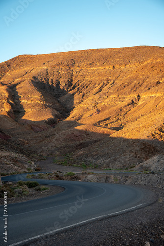 Asphalt winding road and high volcanic mountains at sunset. Morro Jable, Fuerteventura, Canary Islands, Spain. 