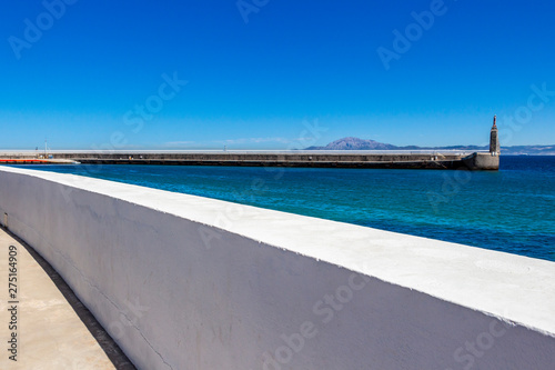 View of Punta del Santo from a Tarifa Port breakwater in Andalusia Spain, the Morocco Mountains across the Straits of Gibraltar in the distance
