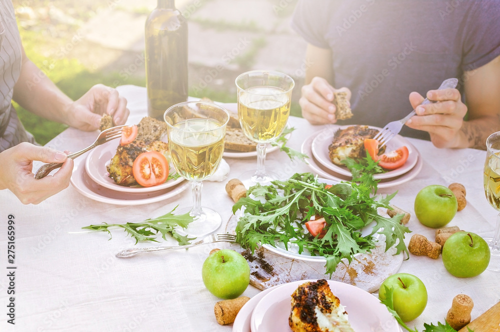 People eat in the garden at the table. Dinner concept with wine in the fresh air. Grilled sea fish and salads with vegetables and herbs. Mediterranean Kitchen. Horizontal shot