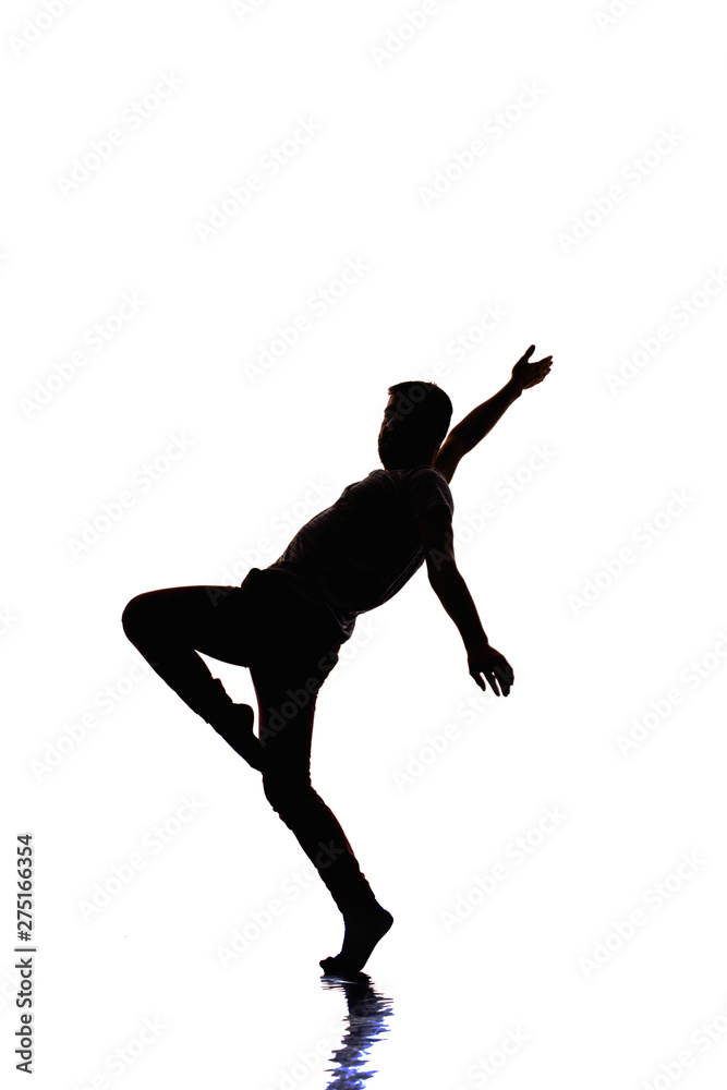 Silhouette performer is doing breakdance on white wall