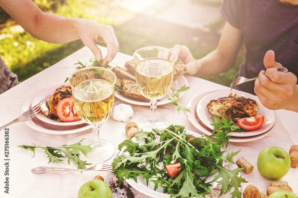 People eat in the garden at the table. Dinner concept with wine in the fresh air. Fish and salads with vegetables and herbs. Mediterranean Kitchen. Horizontal shot
