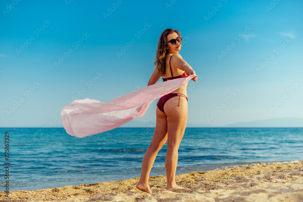 Girl waving with a beach scarf in front of the sea Girl waving with a beach scarf in front of the sea