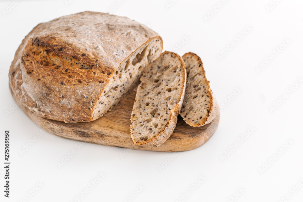 Fresh baked organic whole grain rye bread on wooden cutting board, white background