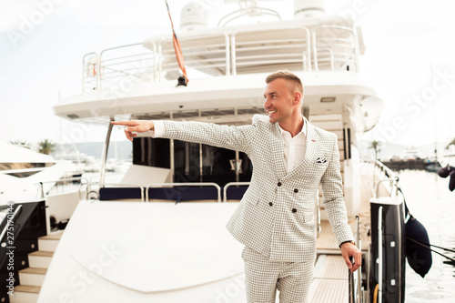 Stylish businessman is standing on his luxury yacht is wearing fashion costume. Montenegro bay photo