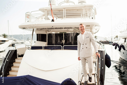 Stylish businessman is standing on his luxury yacht is wearing white fashion costume. Montenegro bay © _chupacabra_