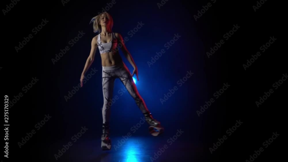 Woman dancing in kangoo jumps shoes against blue spotlight. Slow motion Woman dancing in kangoo jumps shoes against blue spotlight. Slow motion