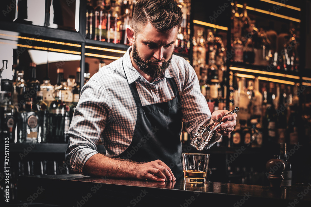 Diligent serious barman is preparing alcoholic beverege for customer. Diligent serious barman is preparing alcoholic beverege for customer.