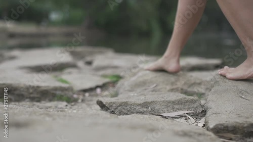 Woman walking barefoot on the rocks by the river or lake during a sunny day. Slow motion Female feet strolling at the nature. Freedom alone scene and relax time concept meditate