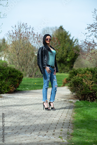 Brunette in sunglasses and black is standing and enjoying the sun in the park © Evgeni Schemberger