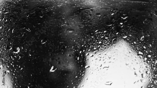 Heterosexual couple hugging each over, black and white, focus on drops of water on glass, vertical panning