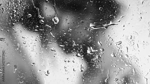 Heterosexual couple hugging each over, black and white, focus on drops of water on glass, vertical panning