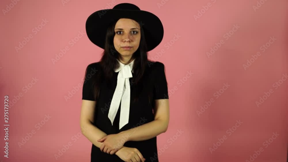 Lady smiling on a pink background. A woman in a black dress and a hat. Lady smiling on a pink background. A woman in a black dress and a hat.