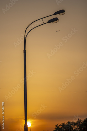 Flying aircraft and lampposts at sunset. Passenger airplane. Bright gradient background
