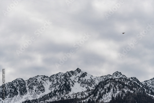 Small helicopter above snow-capped mountains peaks. The Brenta Dolomites. Mountains panorama. Trentino-Alto Adige, Sdtirol, Trento Alps, Italy photo