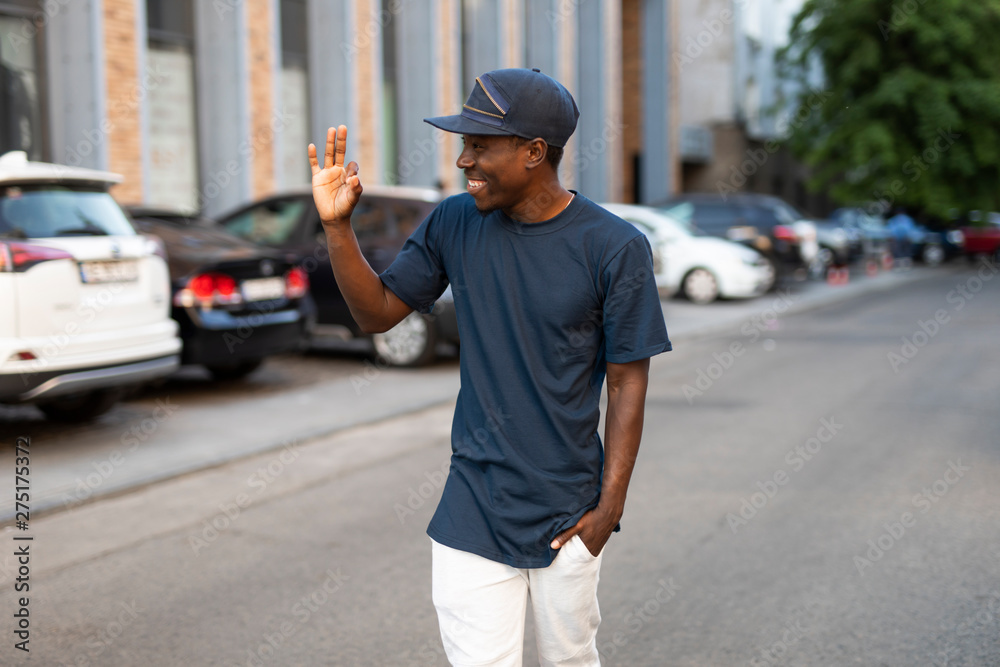 Happy african american man greets a friend waving his hand walking in city street, he glad to see you Happy african american man greets a friend waving his hand walking in city street, he glad to see you