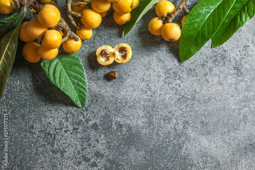 Fresh ripe loquat japanese medlar fruit with branch and leaf on grey rustic table, malta plum, summer fruits concept photo