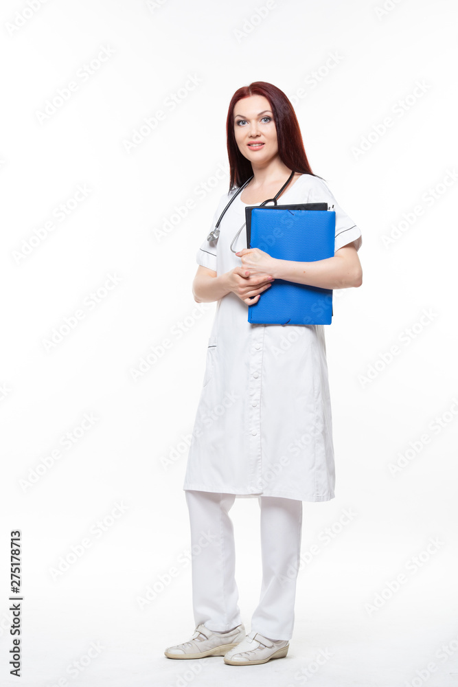 Happy young female family doctor holds blue folder with documents, has friendly expression, isolated white background. Medicine concept. Happy young female family doctor holds blue folder with documents, has friendly expression, isolated white background. Medicine concept.