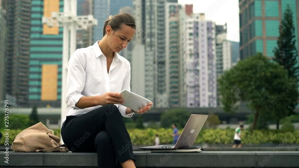 Young, pretty businesswoman working on laptop and tablet in city Young, pretty businesswoman working on laptop and tablet in city