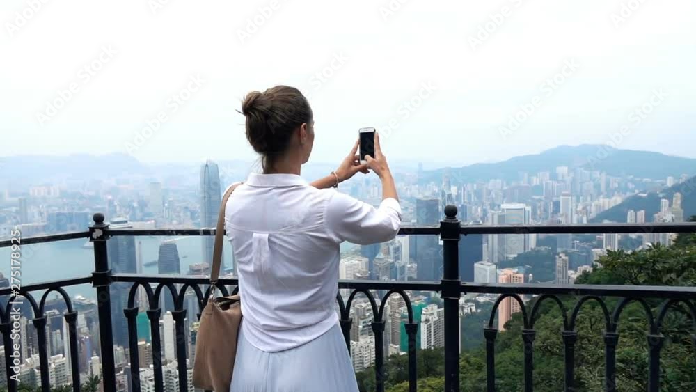 Young woman taking photo with cellphone of Hong Kong skyline, slow motion Young woman taking photo with cellphone of Hong Kong skyline, slow motion