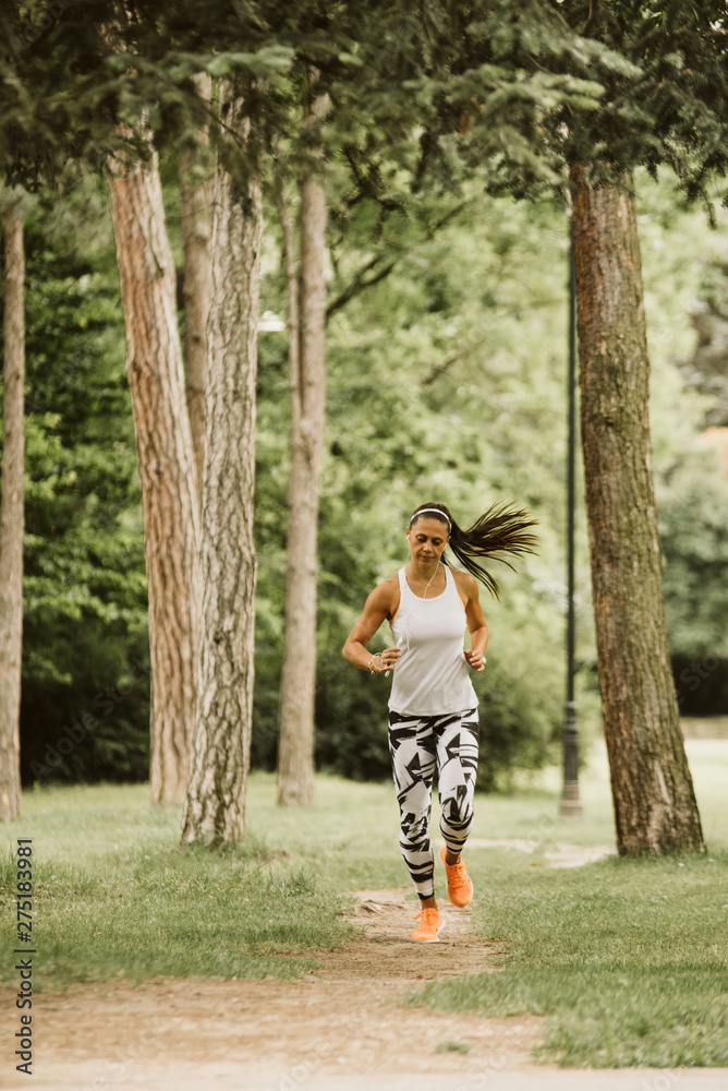 A beautiful fitness girl runs in the park. Nature and healthy life A beautiful fitness girl runs in the park. Nature and healthy life