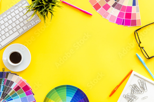 Pallet, keyboard, glasses, cup of coffee and tools for designer work on yellow desk background top view copyspace frame