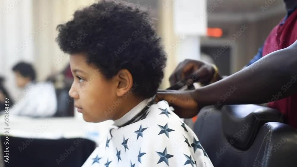 Boy in the african barbershop. Cute mixed boy makes a haircut in the ...