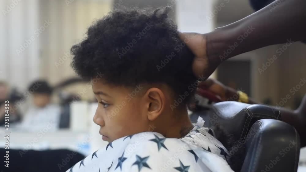 Boy in the african barbershop. Cute mixed boy makes a haircut in the African salon. Hair style. Haircut by machine for children. School boy hair style. Haircut by scissor Stock Video | Boy in the african barbershop. Cute mixed boy makes a haircut in the African salon. Hair style. Haircut by machine for children. School boy hair style. Haircut by scissor Stock Video |