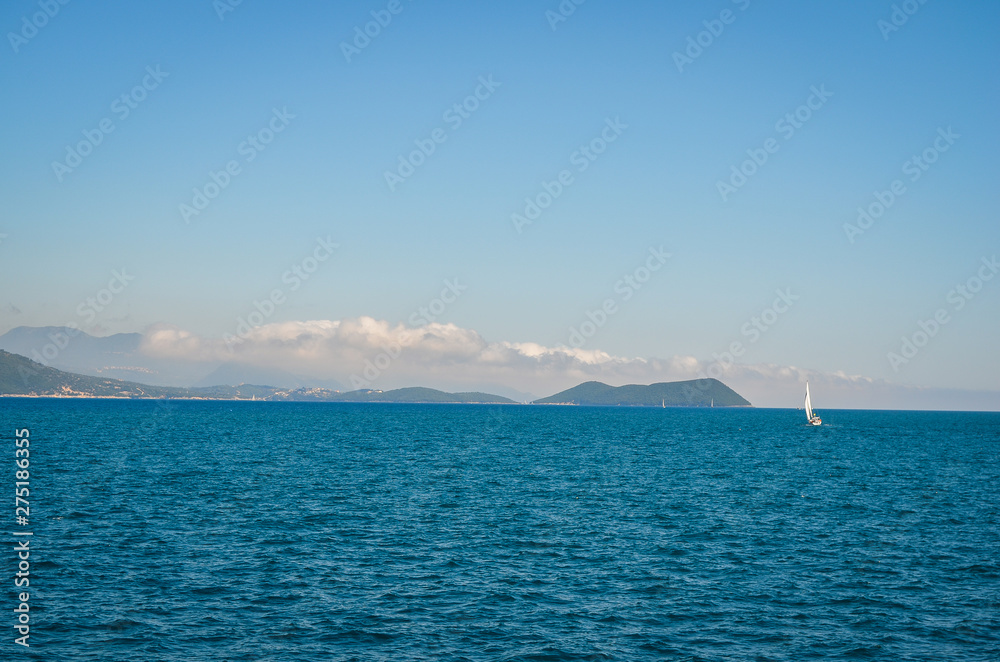  Corfu,  Greece seashore  and sailing boat on   sea  agains  blue sky  during summer  .