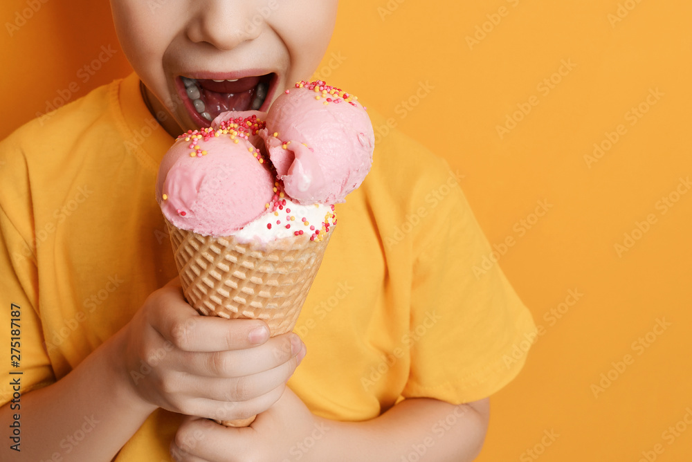 Baby boy kid eating strawberry ice-cream in waffles cone happy screaming laughing on yellow background