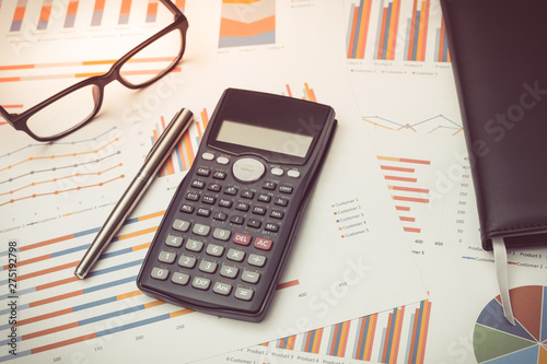 Data analysis with calculator from charts on desk at office. business concept.