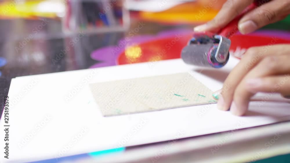 Male hands using a roller over lino for artistic printwork