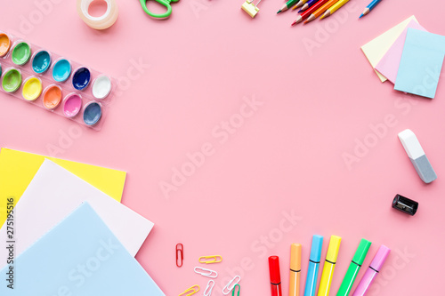 School supplies stationery, colour pencils, paints, paper on pink background, back to school concept with free copy space for text, modern elementary education. Kids desk, flat lay, top view, mockup.