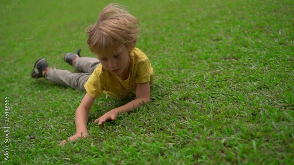 Superslowmotion shot of two little boys have fun on a lawn. They roll down the hill Superslowmotion shot of two little boys have fun on a lawn. They roll down the hill