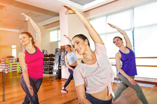 Group of young sporty attractive people practicing yoga lesson with instructor  standing together in exercise  working out  full length  studio background  close up