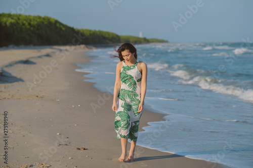 A lonely girl is walking on wet sand. Beautiful asian woman walking on the beach.