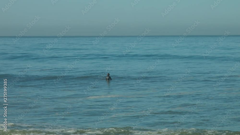 Slow motion shot of a surfer sitting on his surf board in the lineup waiting for a wave. Slow motion shot of a surfer sitting on his surf board in the lineup waiting for a wave.