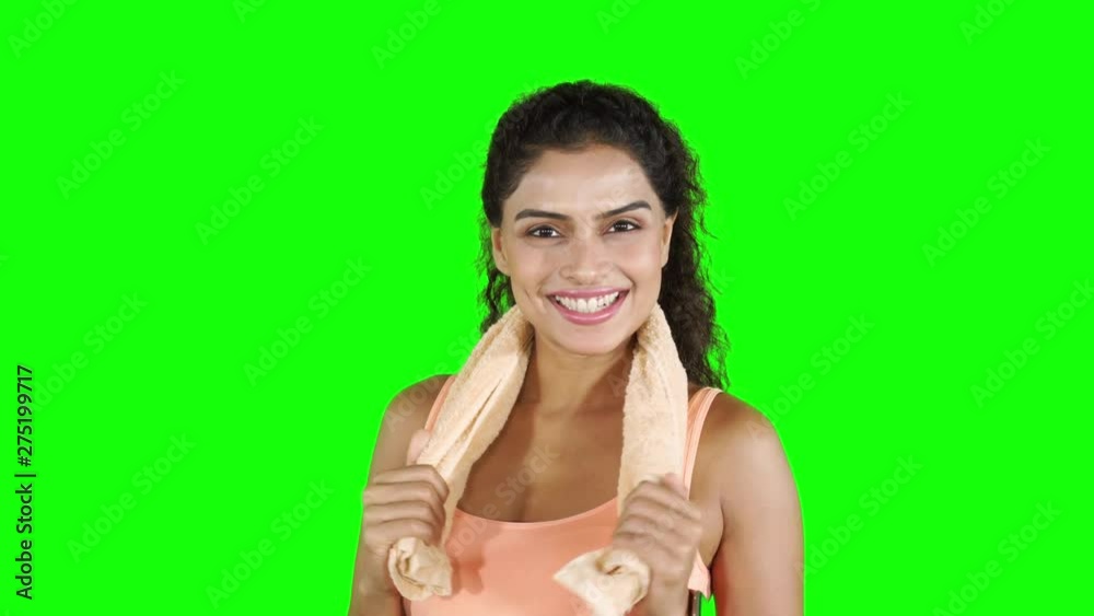 Attractive healthy woman smiling at the camera while wearing sportswear and holding a towel on her neck. Shot in 4k resolution with green screen background Attractive healthy woman smiling at the camera while wearing sportswear and holding a towel on her neck. Shot in 4k resolution with green screen background