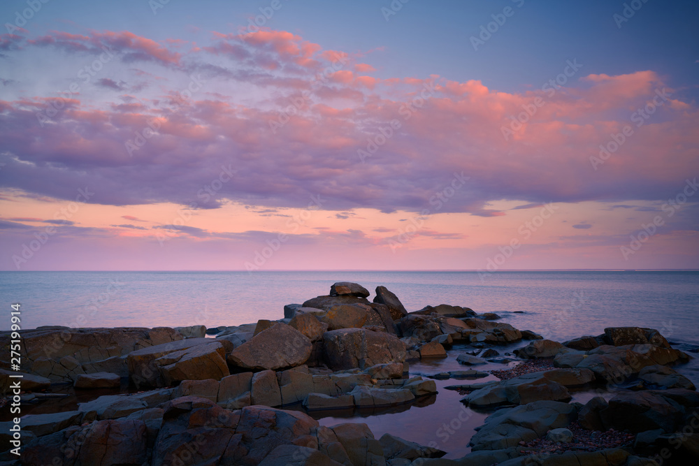 Beautiful pink sunset clouds over the rocky beach