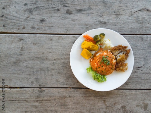 Fried rice, fried chicken  vegetables on a wooden table