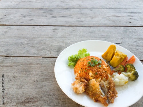 Fried rice, fried chicken  vegetables on a wooden table