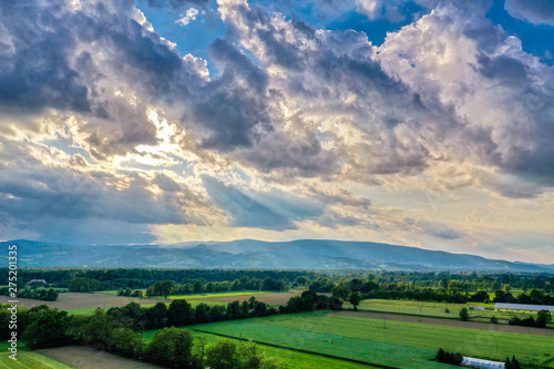 Dramatic clouds above rural landscape, sun rays through clouds