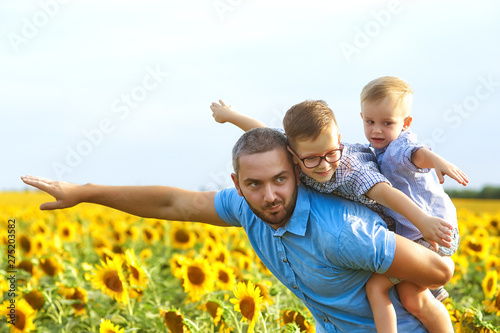 Young father with his sons on a walk . A parent holds two sons in his arms . Father s day.  Happy father