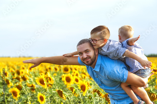 Young father with his sons on a walk . A parent holds two sons in his arms . Father's day. Happy father