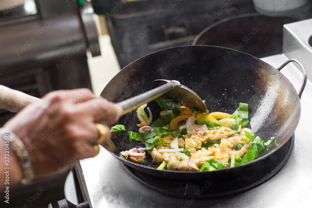 Man hand is cooking Asian style in a pan Man hand is cooking Asian style in a pan
