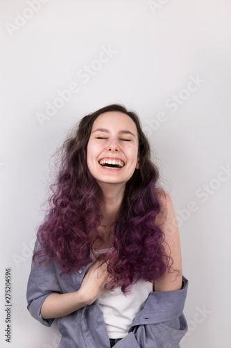 Young girl laughs. Coloring purple hair. Gray background