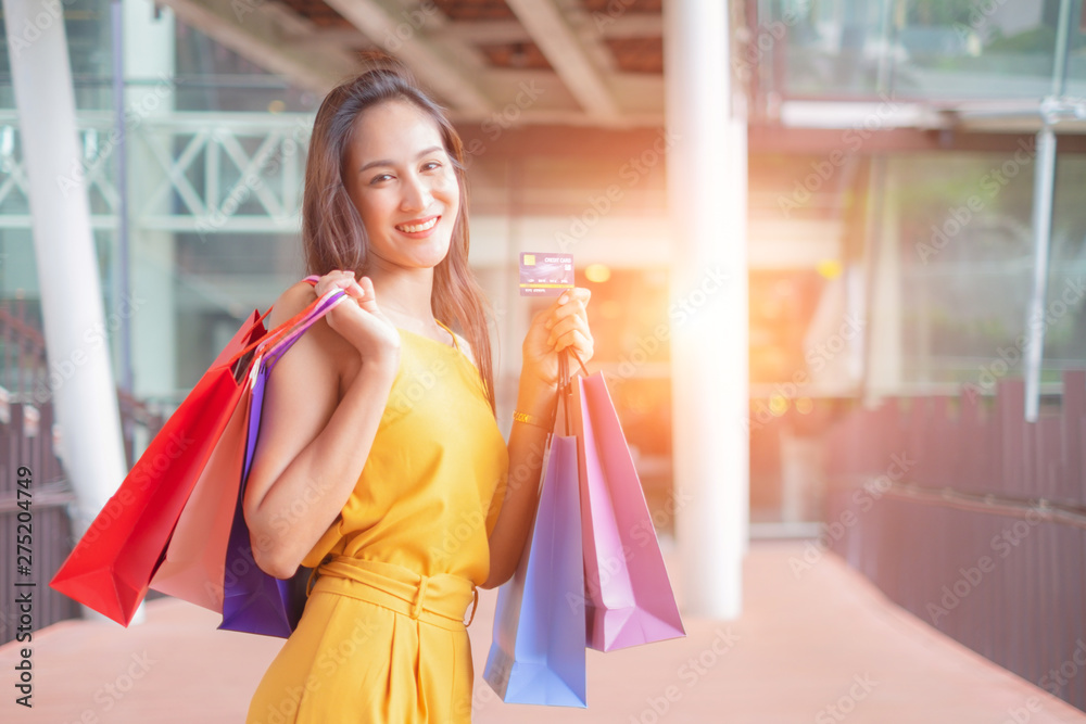 Beautiful women with shopping bags and credit card enjoying in shopping standing outdoors of shopping mall, shopping concept Beautiful women with shopping bags and credit card enjoying in shopping standing outdoors of shopping mall, shopping concept