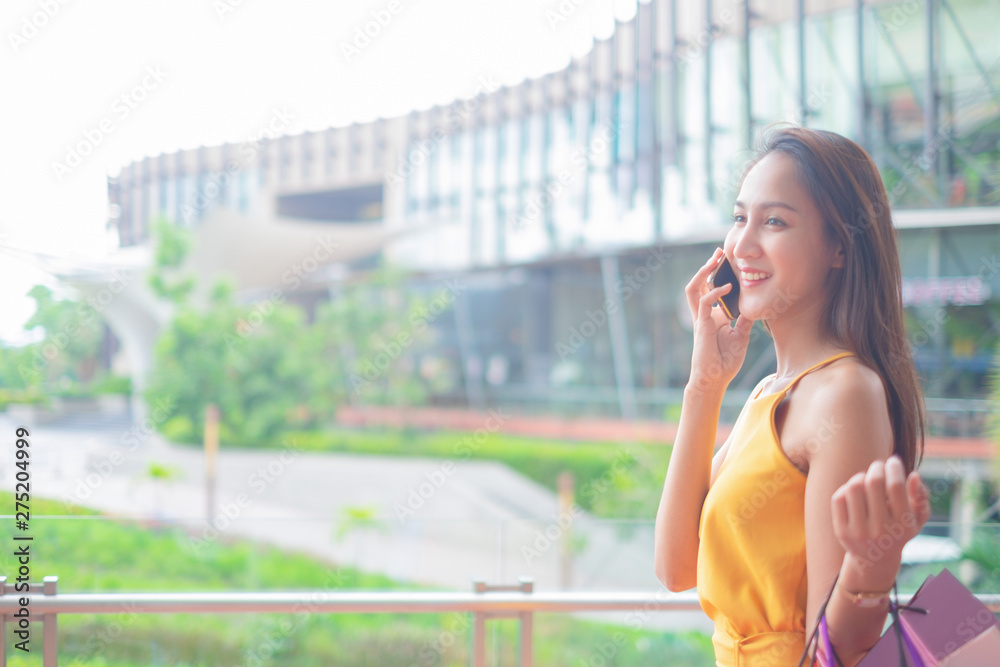 Beautiful women with shopping bags and smartphone enjoying in shopping standing outdoors of shopping mall, shopping concept Beautiful women with shopping bags and smartphone enjoying in shopping standing outdoors of shopping mall, shopping concept